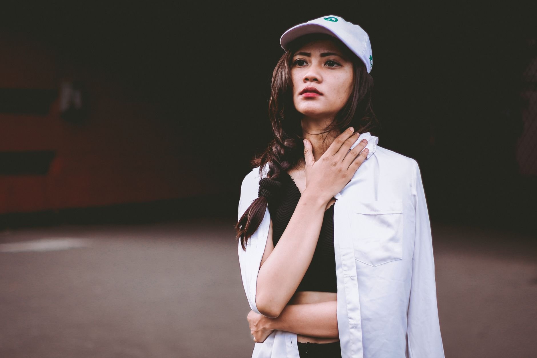 Confident young woman in casual streetwear posing against a dark background